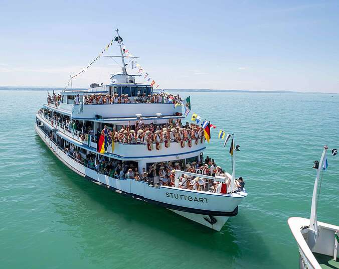 Geschmücktes Schiff mit vielen Passagieren auf Wasser