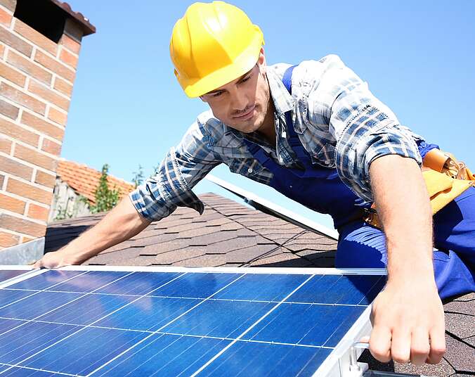 Handwerker montiert Solarmodul auf Dach