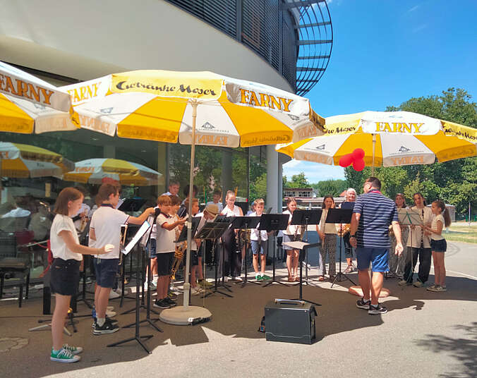 Junge Musikerinnen und Musiker spielen vor der Musikschule.