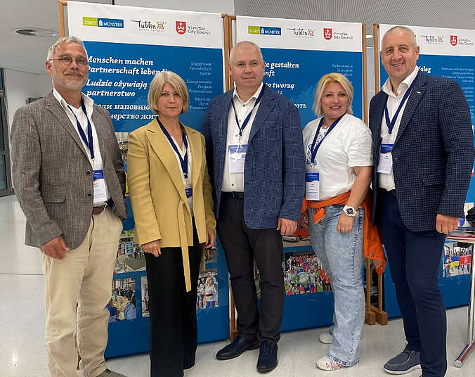 Drei Männer und zwei Frauen stehen als Gruppe nebeneinander.