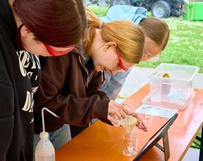 Schülerinnen untersuchen eine Flüssigkeit mit Laborutensilien
