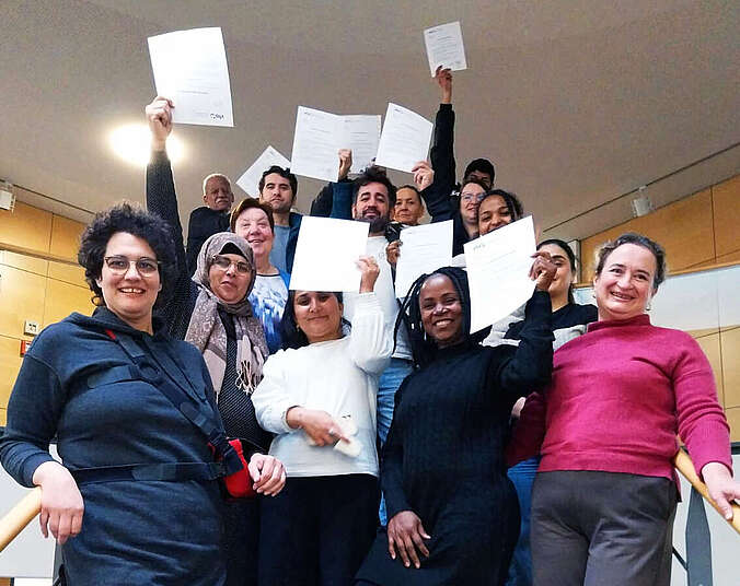 Gruppenbild auf Treppe, Menschen strecken Urkunden in die Höhe