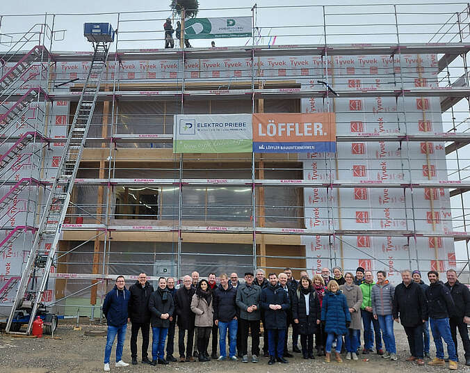 Eine Gruppe Männer und Frauen stehen vor einem Haus.