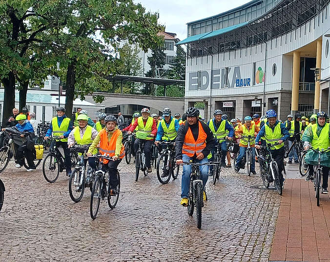 Männer und Frauen mit gelben Westen auf Fahrrädern