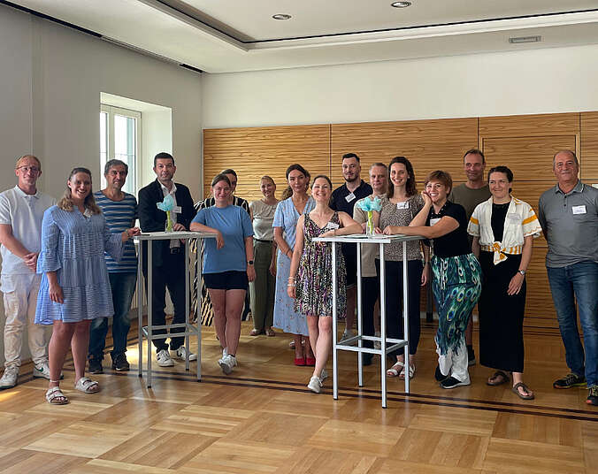 Gruppe von Männern und Frauen an Stehtischen.q