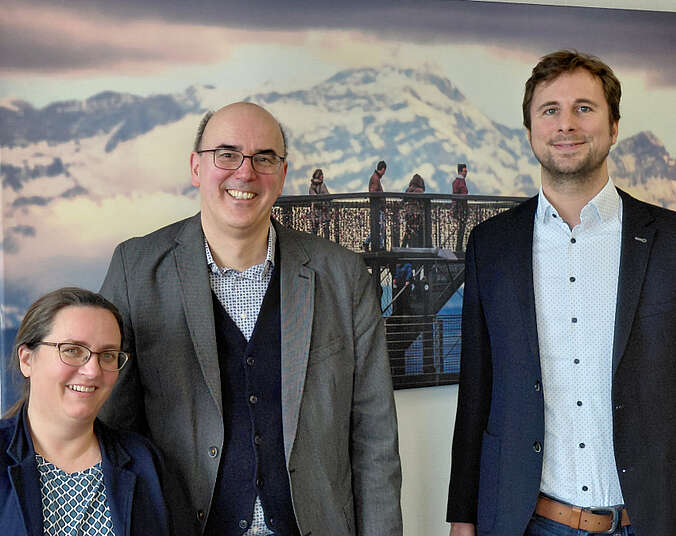 Zwei Männer und eine Frau vor einem Bild