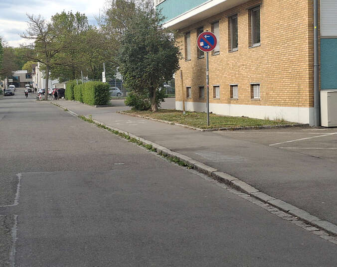 grauer Straßenbelag vor einem gelben Gebäude