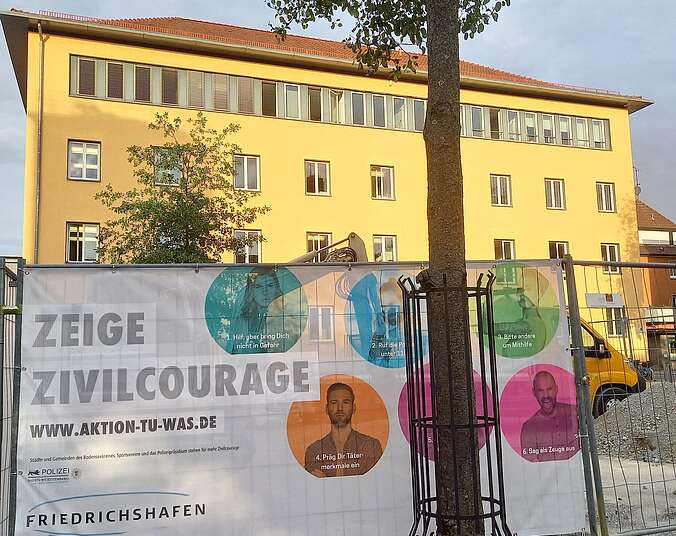 Banner Aktion Zivilcourage an Bauzaun vor gelbem Haus