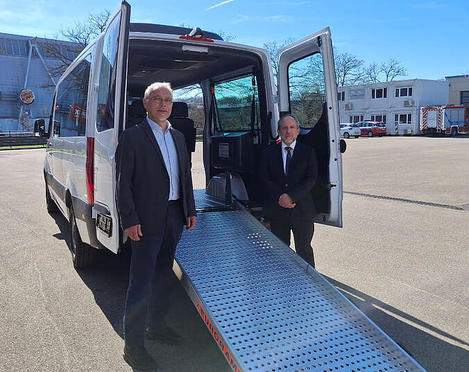 Zwei Männer an der Rückseite des Busses mit einer Auffahrrampe.